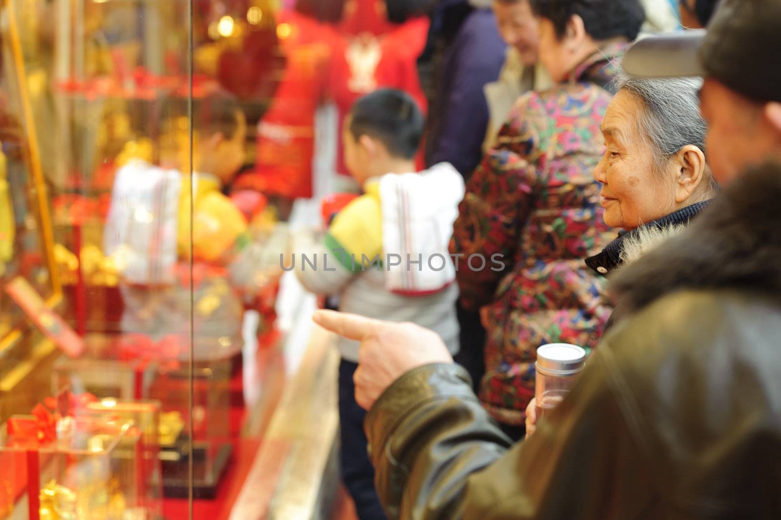 A Woman stop to look in the window of a gold shop on a busy pedestrian shopping street in downtown.