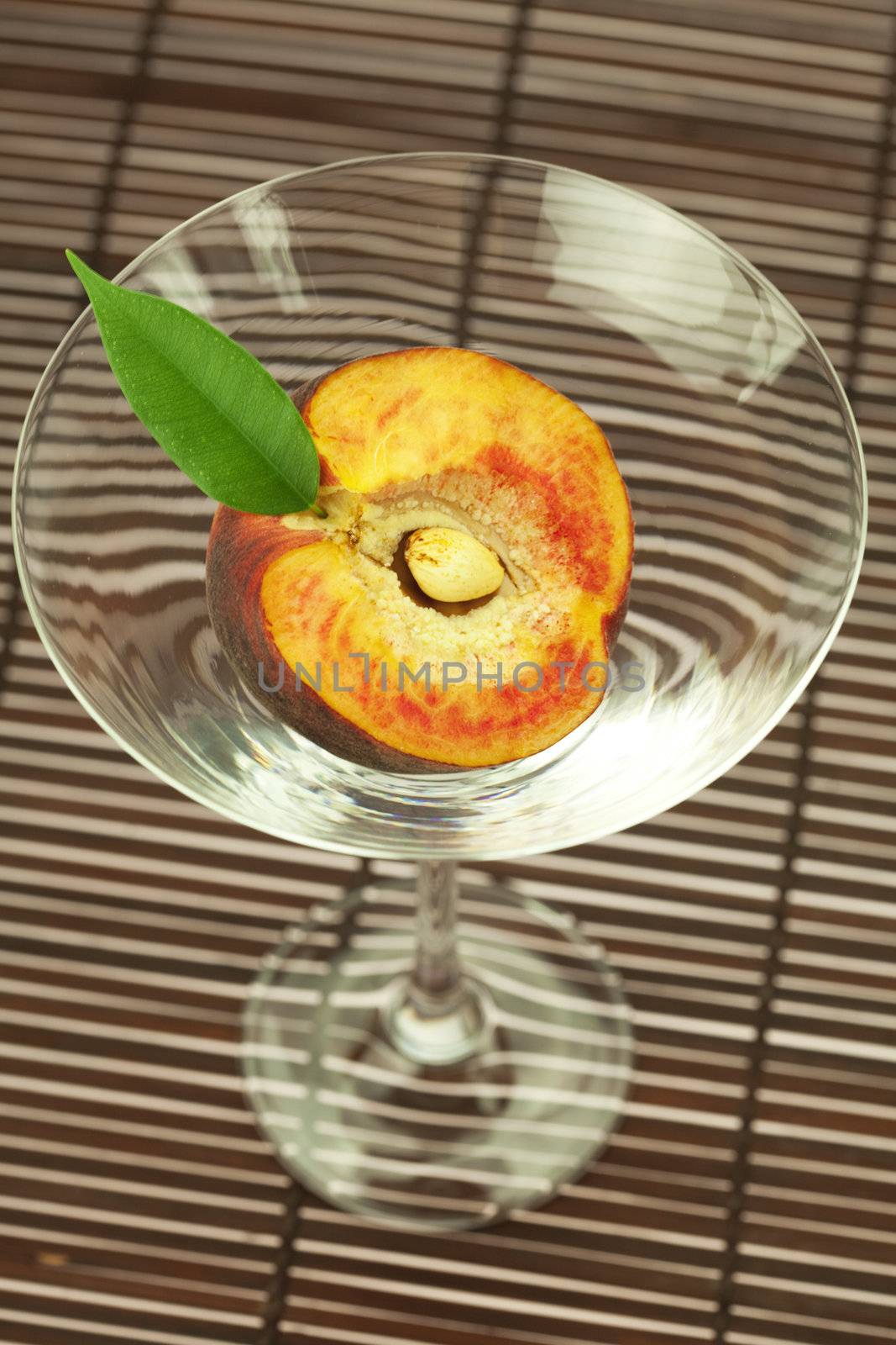 peach in the martini glass on a bamboo mat by jannyjus