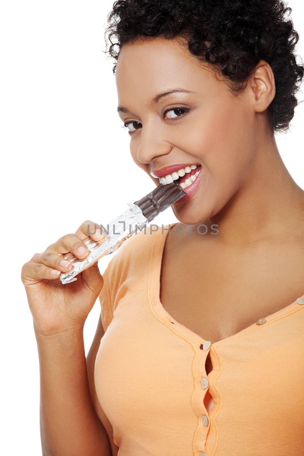Portrait of a beautiful young woman eating a chocolate, smiling to the camera, over a white backgroung.