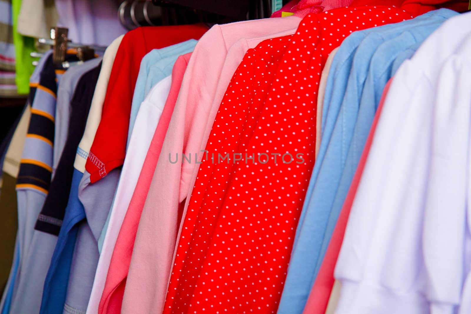 a lot of bright children's clothing on a hanger in the store