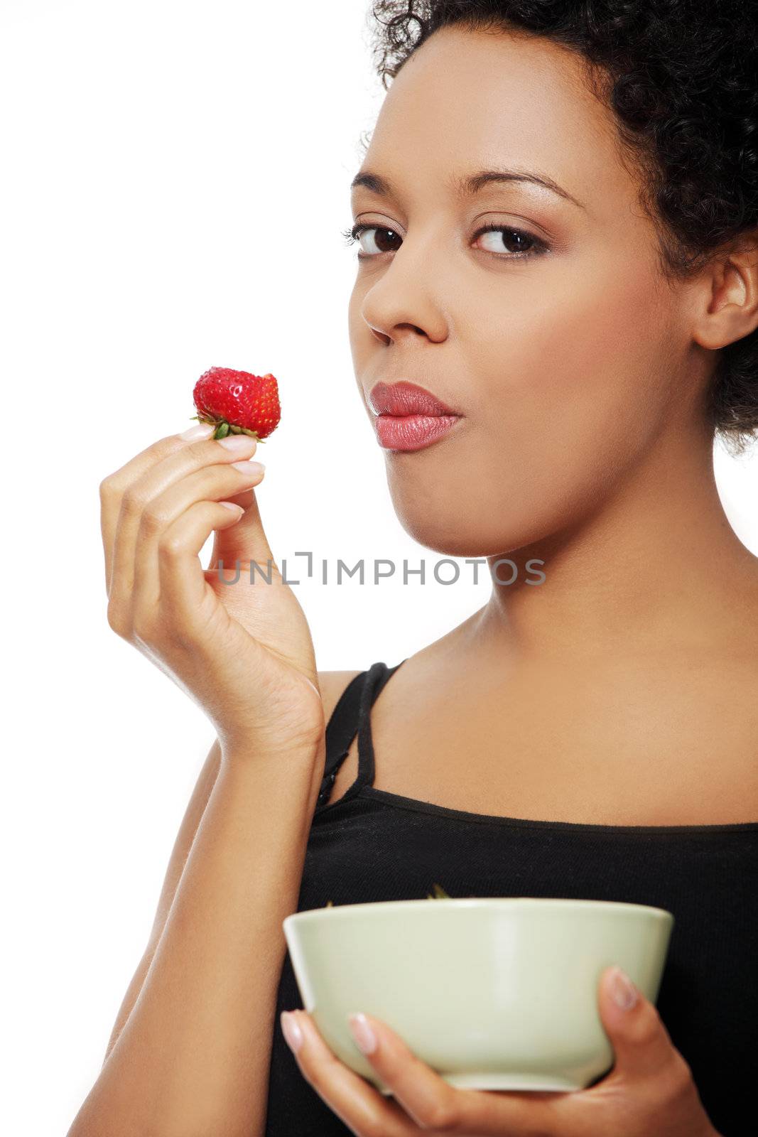 Face closeup portrait of a beautifyl young woman taking a bite of a strawberry, over a white background.