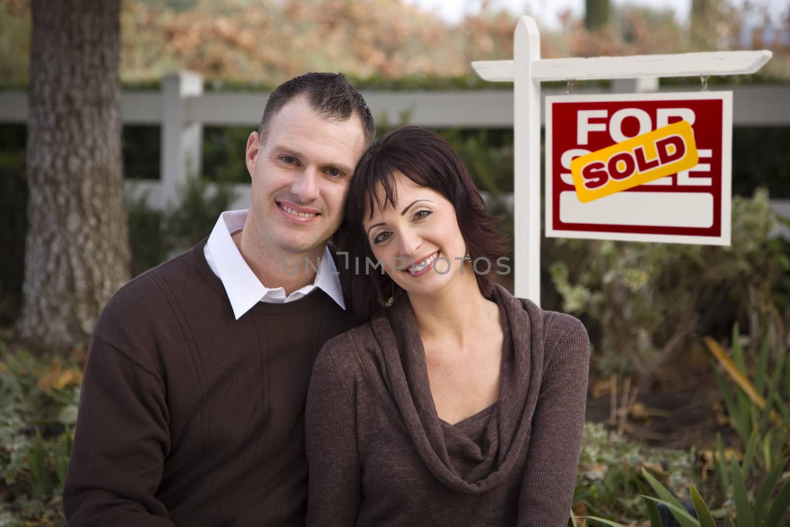 Happy Couple in Front of Sold Real Estate Sign by Feverpitched