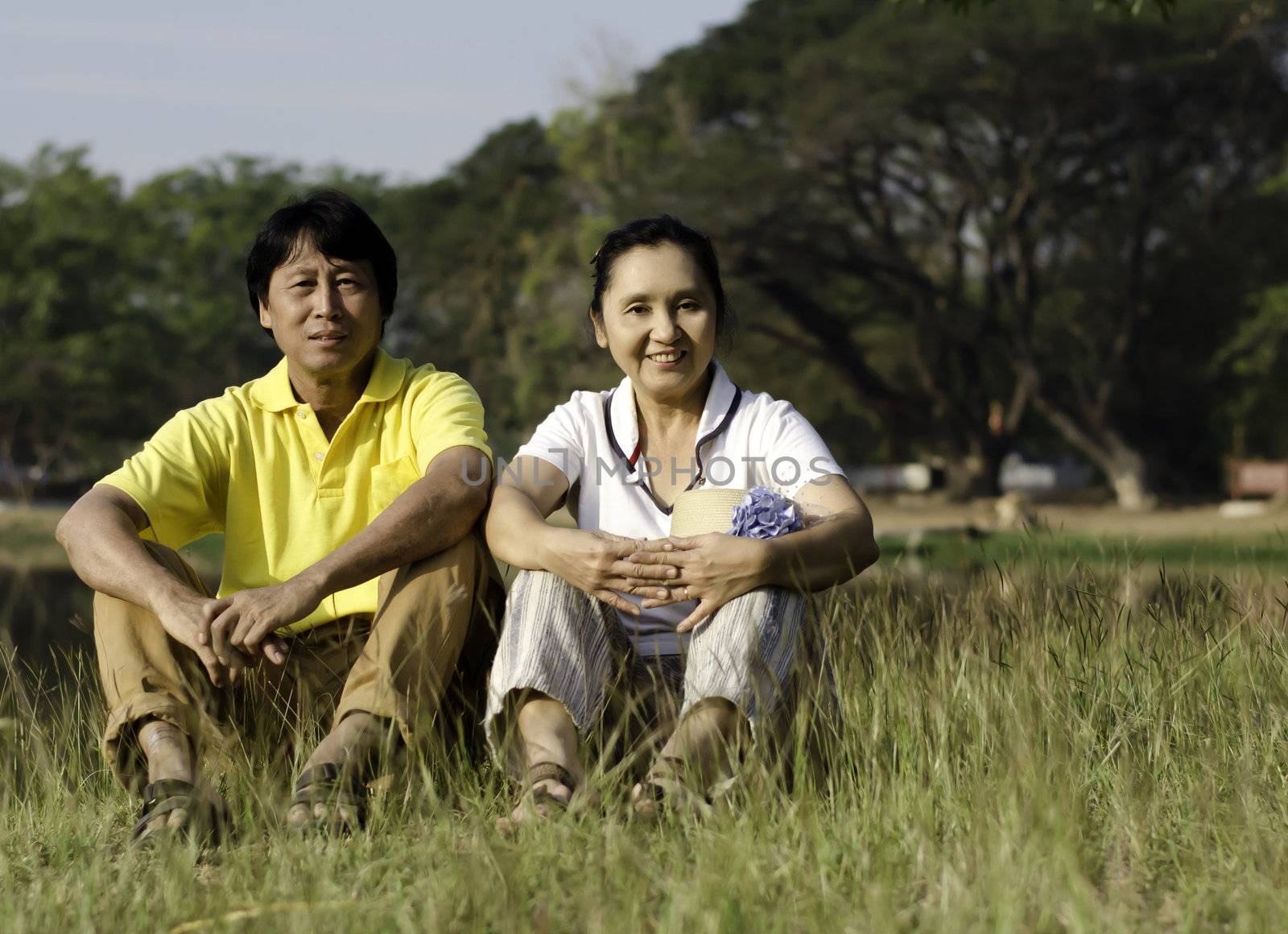 Portrait of beautiful couple sitting on ground in park relaxing 