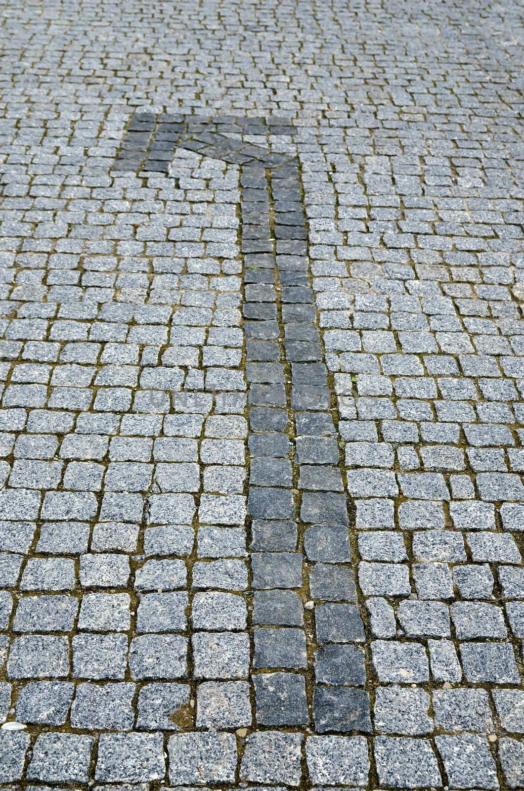 cobbled road with arrow as background by mycola