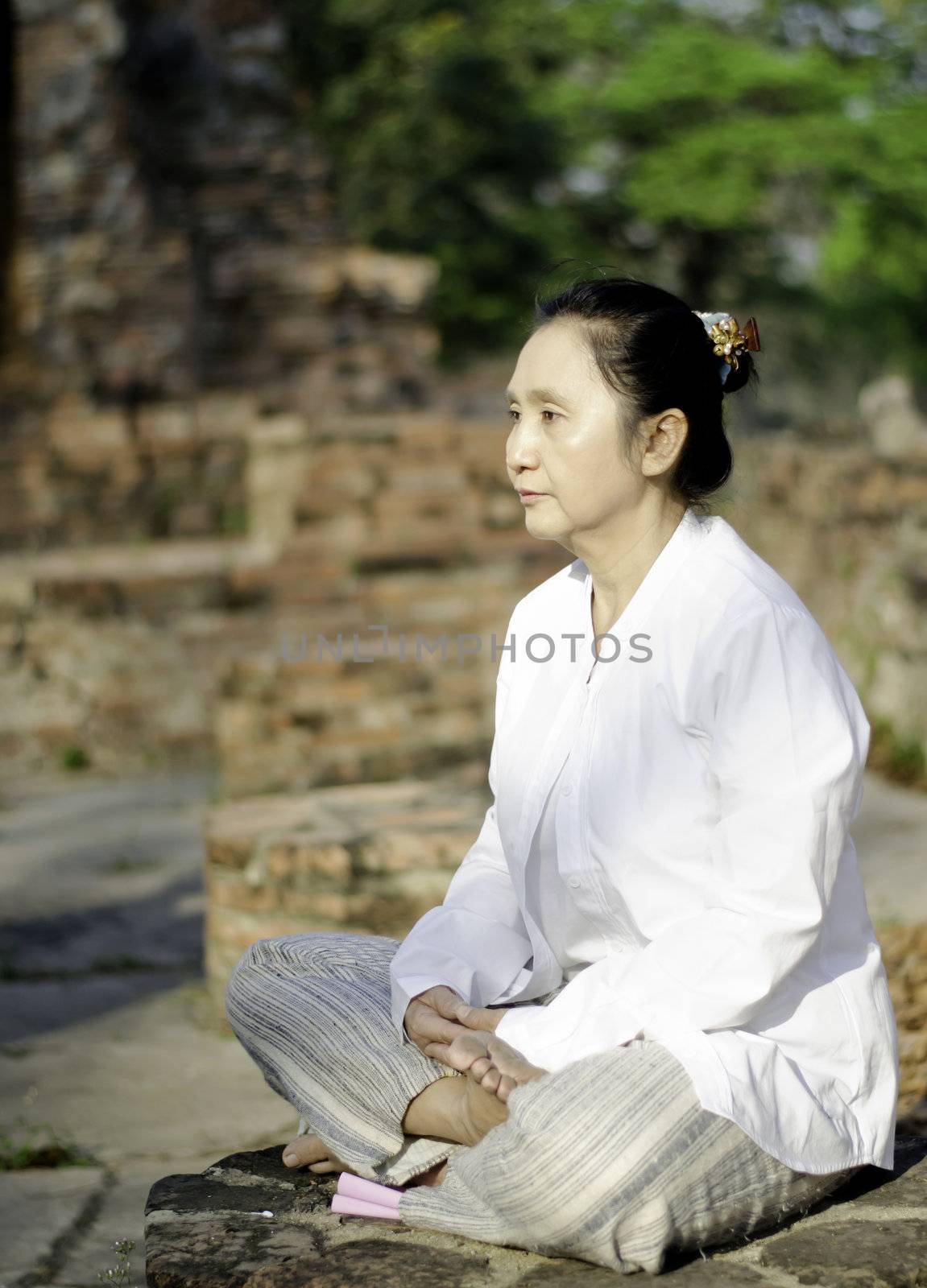 Buddhist woman meditating by siraanamwong
