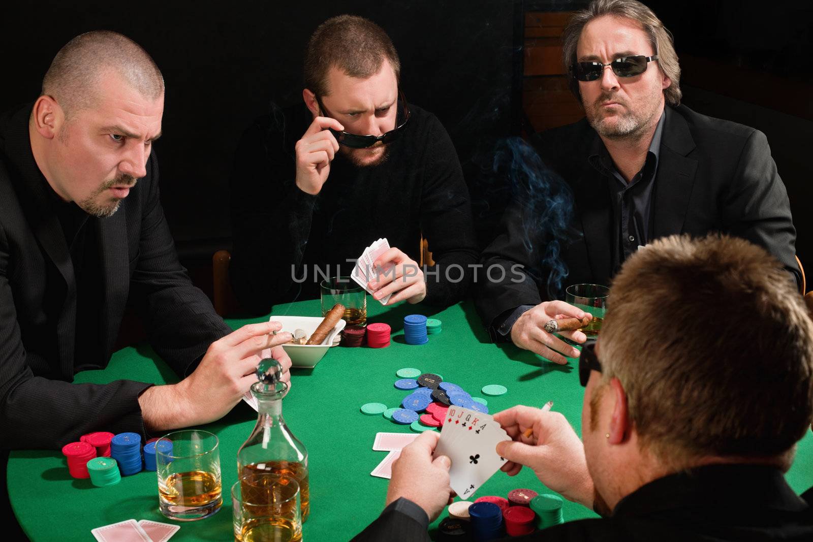 Photo of three male poker players staring across in anger at the fourth player. Cards have been altered to be generic.