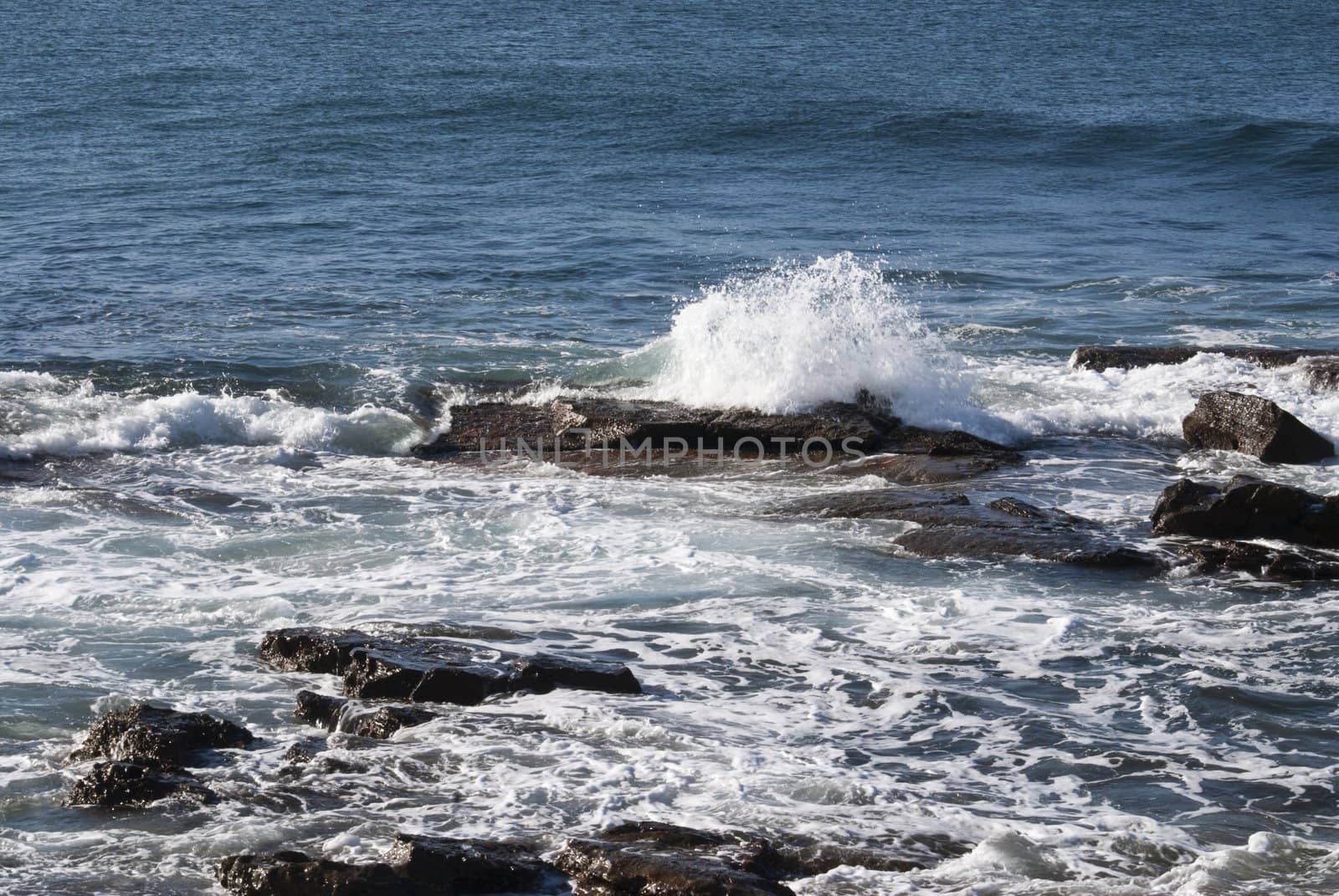 Rolling waves splash over rocks near the shore