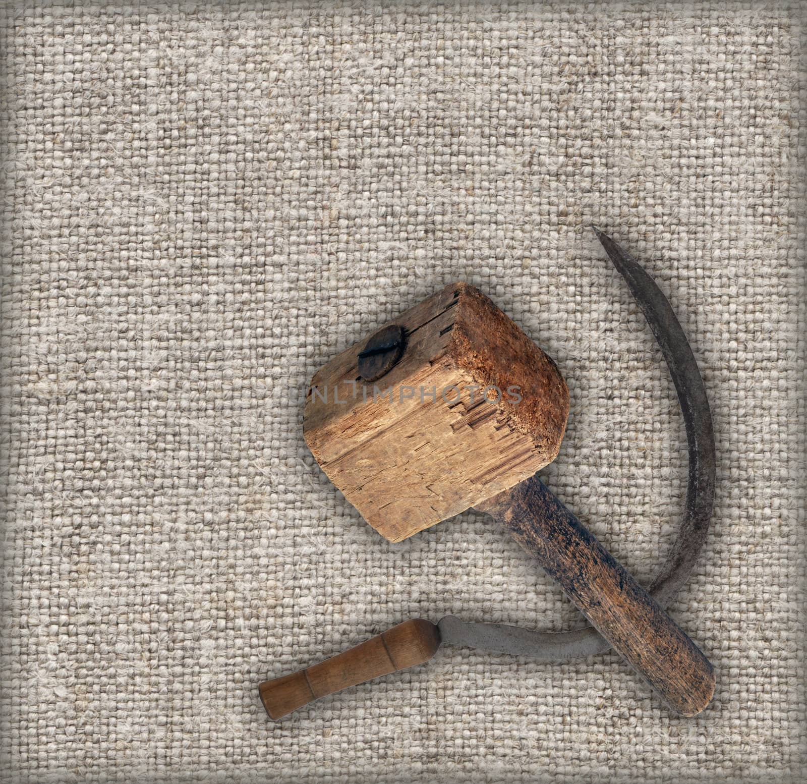 Old tools on canvas: sickle and wooden hammer mallet. Made in the USSR, Russia, Siberia, in the mid-20th century