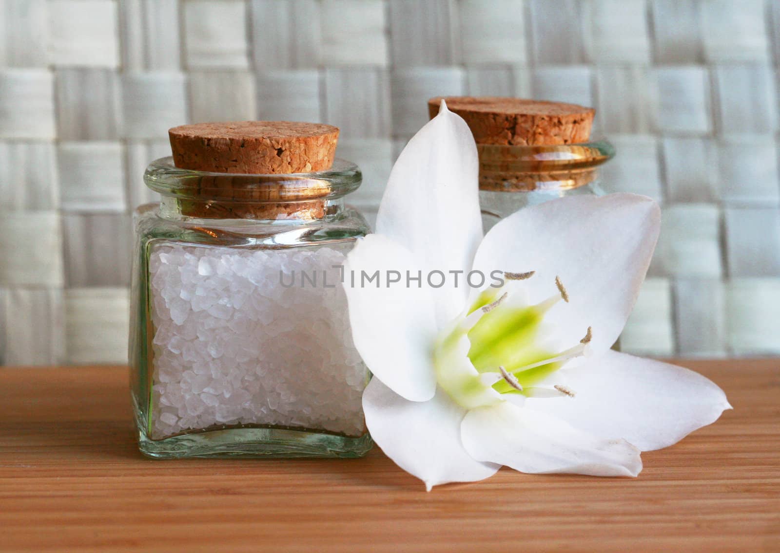 Bottles of sea salt and oil with white flower in spa composition 