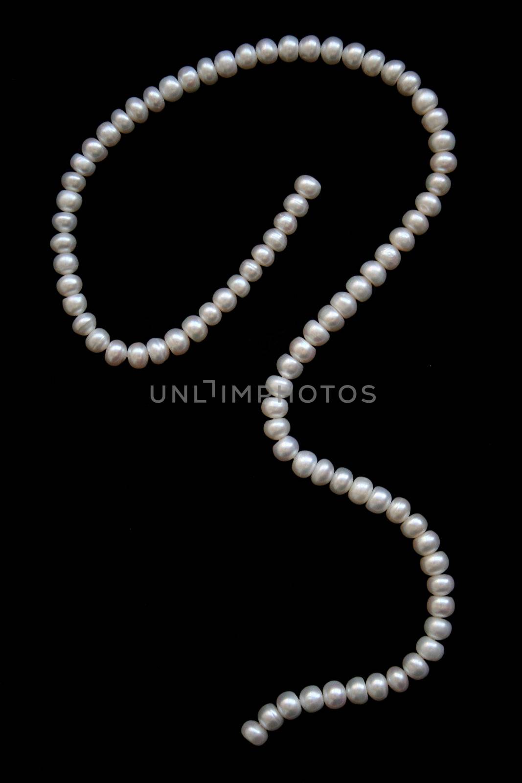 White pearls on the black silk as background 