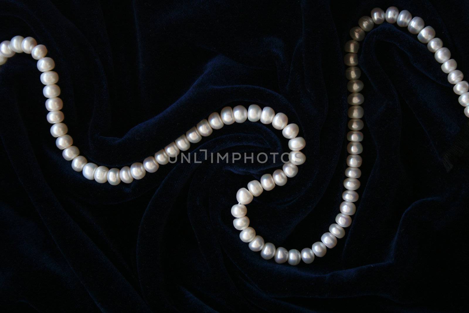 White pearls on the black silk as background 