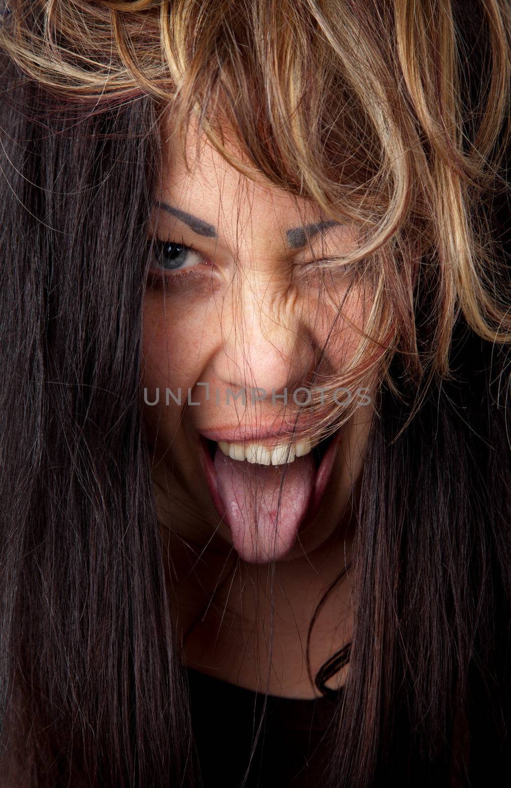 Portrait of young excited female with her tongue out and winking at camera