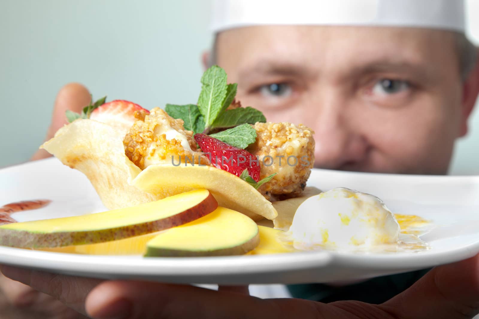 Chef holding a plate with fruit dessert, focus on dish
