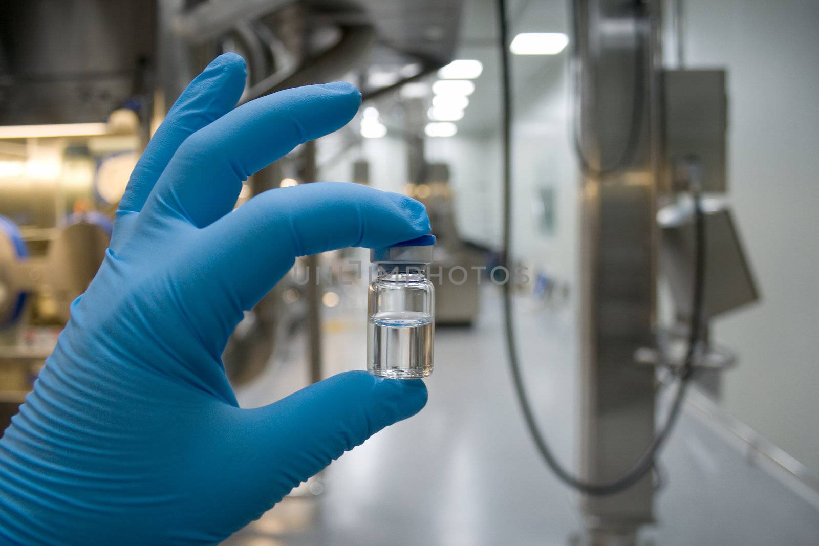 Hand in rubber glove holding a bottle of medicine by Nickondr