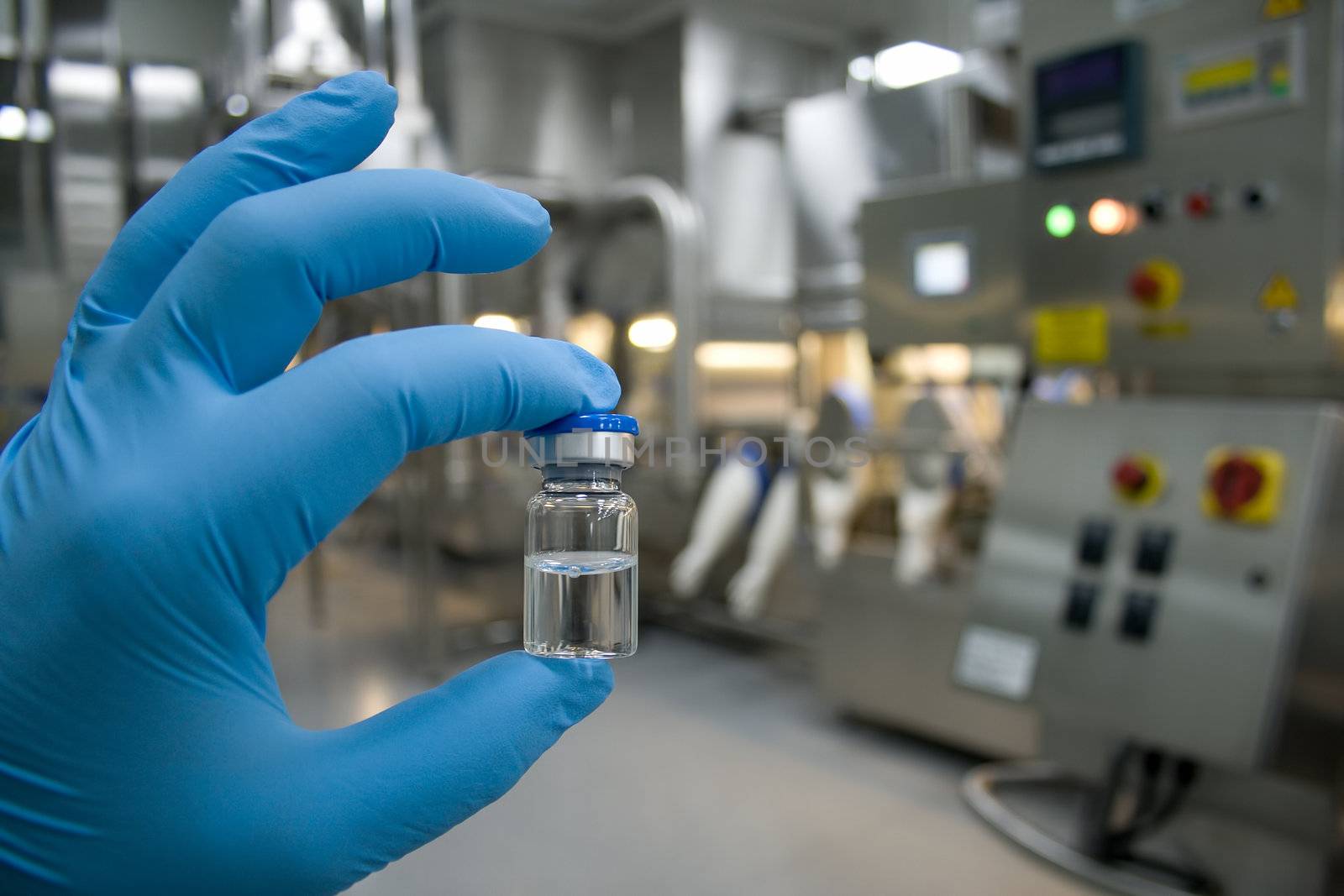 Hand in rubber glove holding a bottle of medicine against the background of the production line drugs