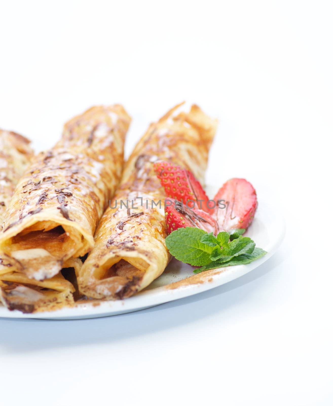 Pancake tubules with a strawberry, glaze and leaflets of mint