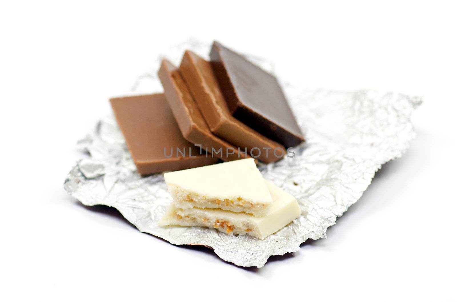 Slices of white, milk and dark chocolate on a foil