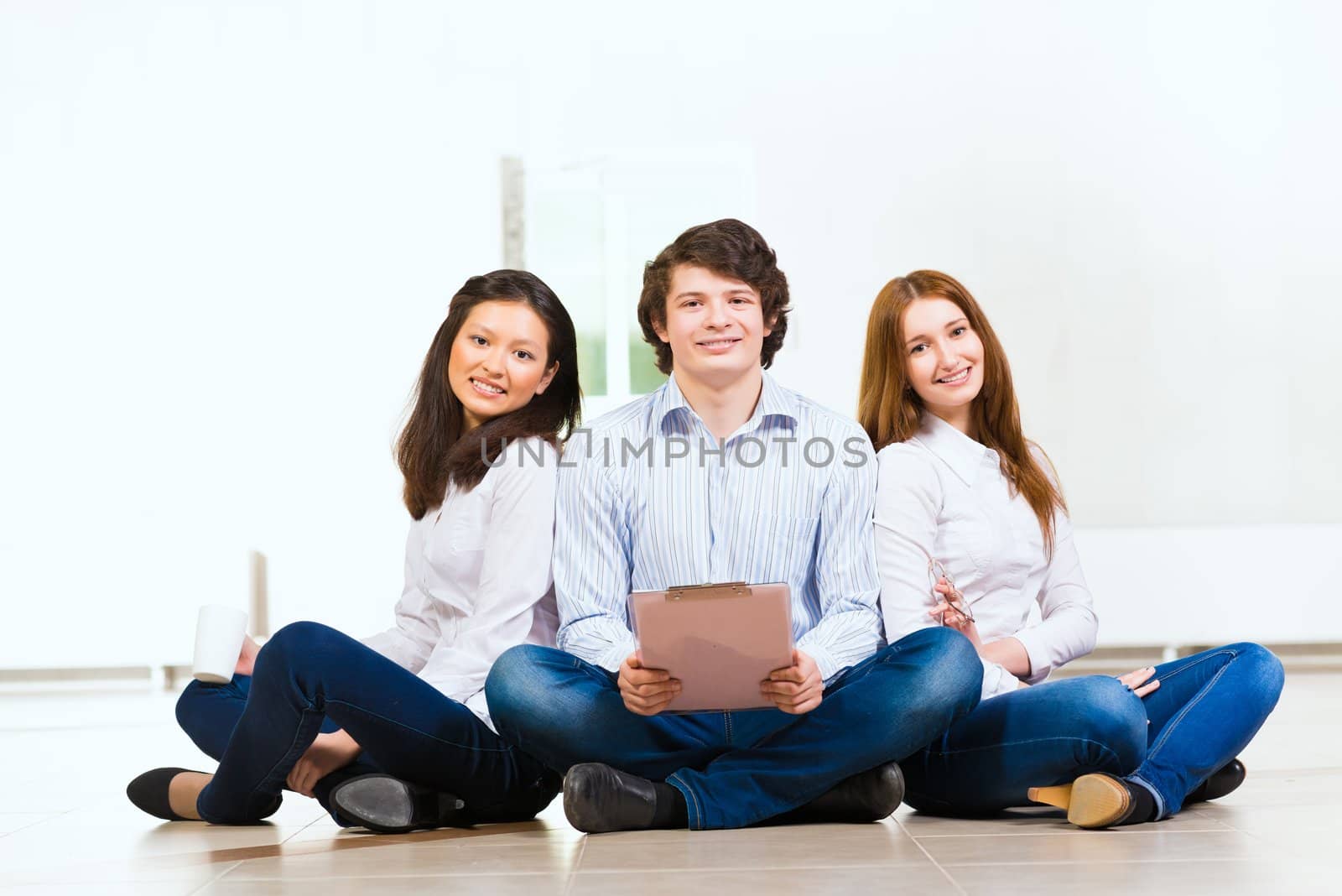 portrait of a group of young people sitting on the floor, man and two attractive women