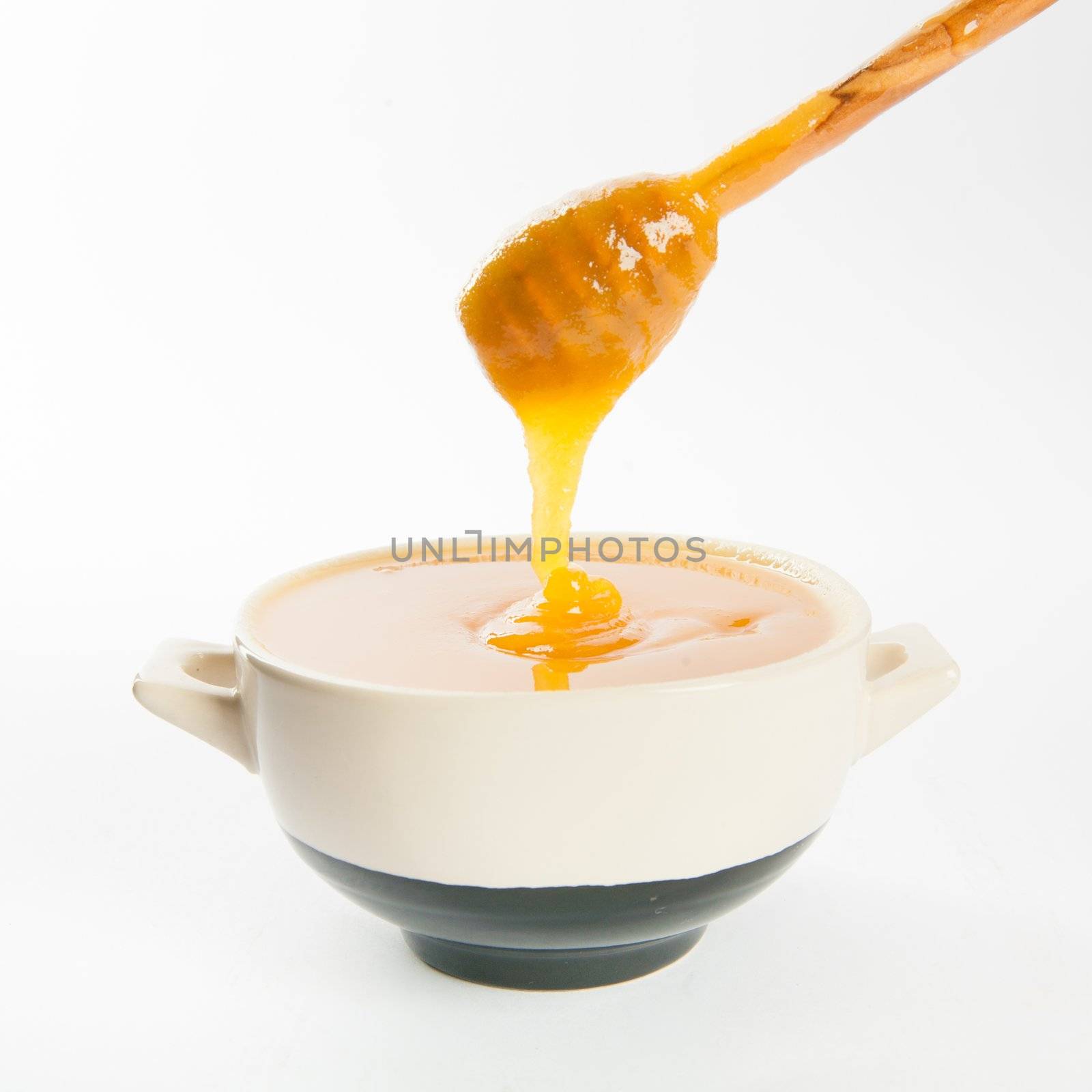 juicy honey in a cup and spoon on white background