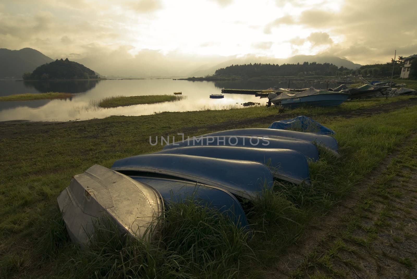 rural warm morning scenery with blue boats close to mountain lake's  waters, Lake Kawaguchi, Japan