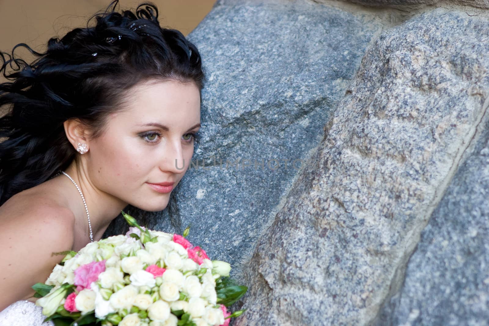girl with rose bouquet near the stone wall