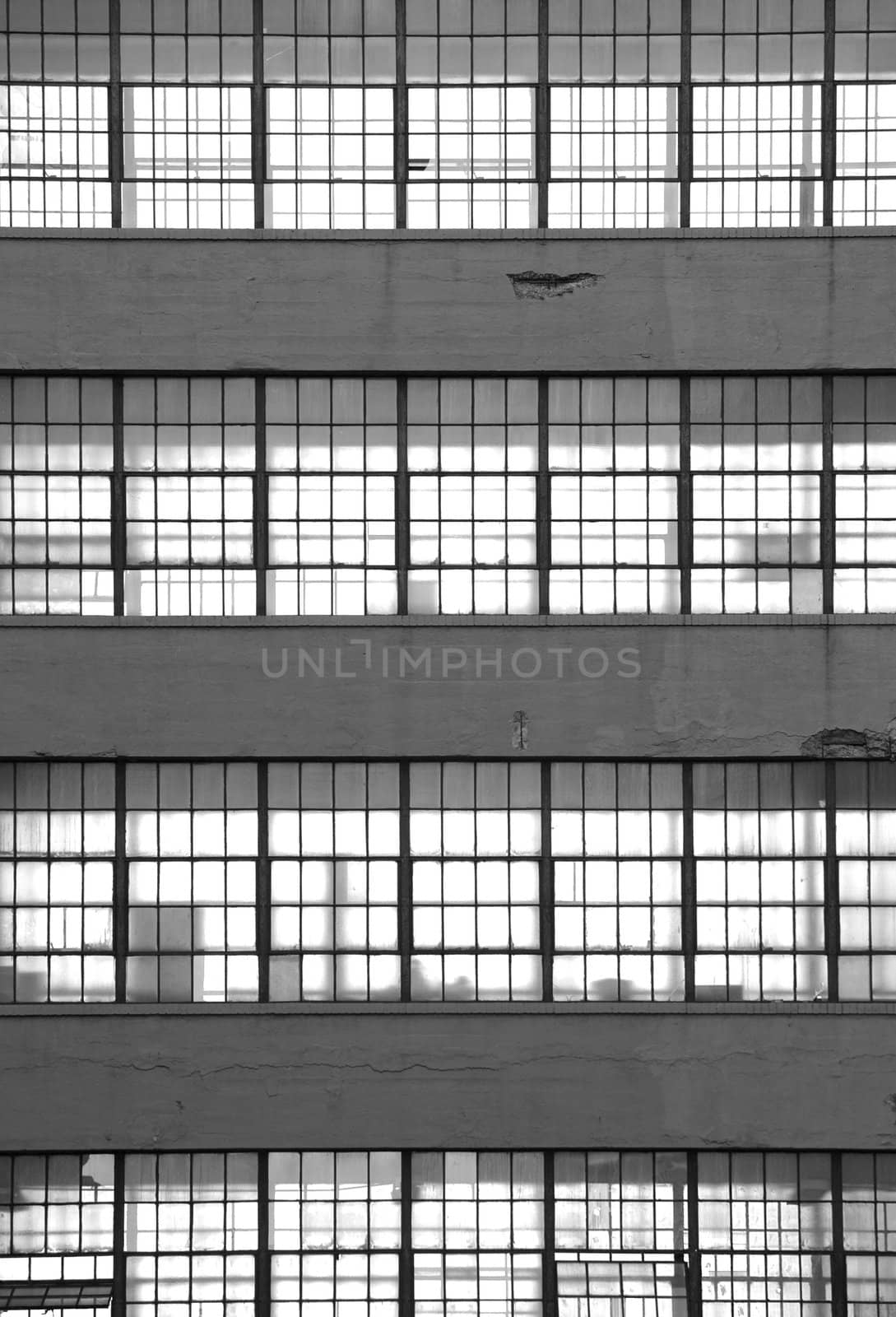 Black and white image of a stack of office windows. Light shines through silhouetting office equipment.