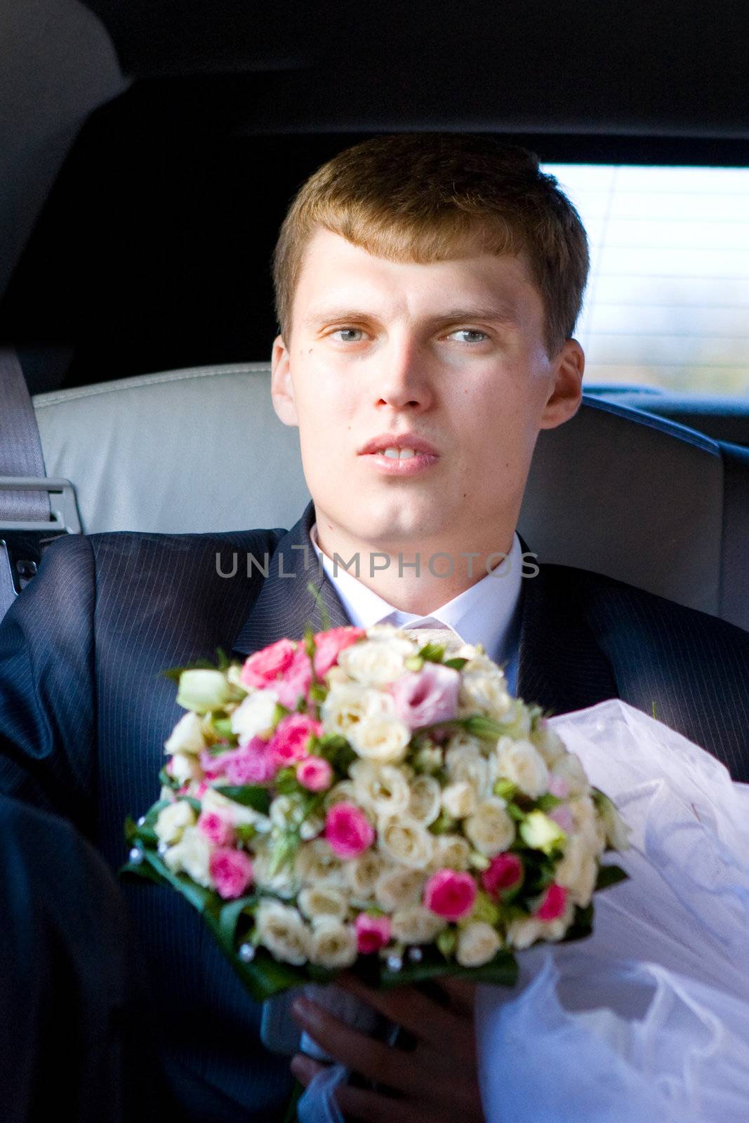 grrom with flower bouquet in the car