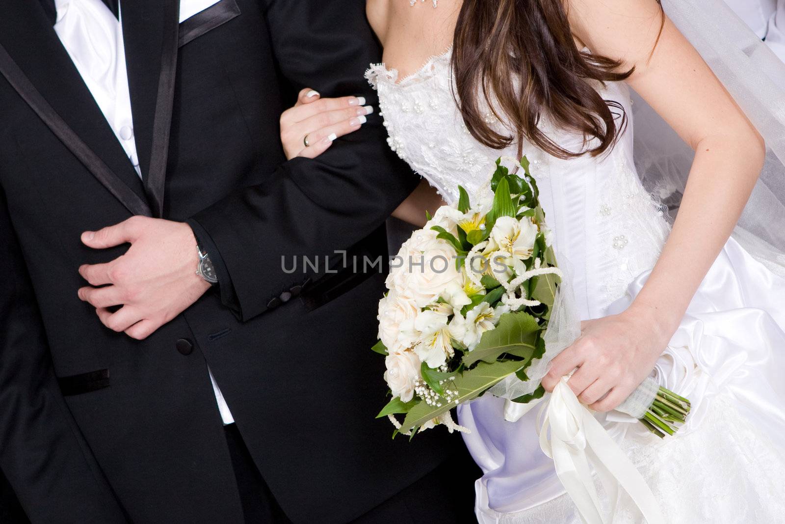 hands of a groom and a bride with a wedding flower bouquet