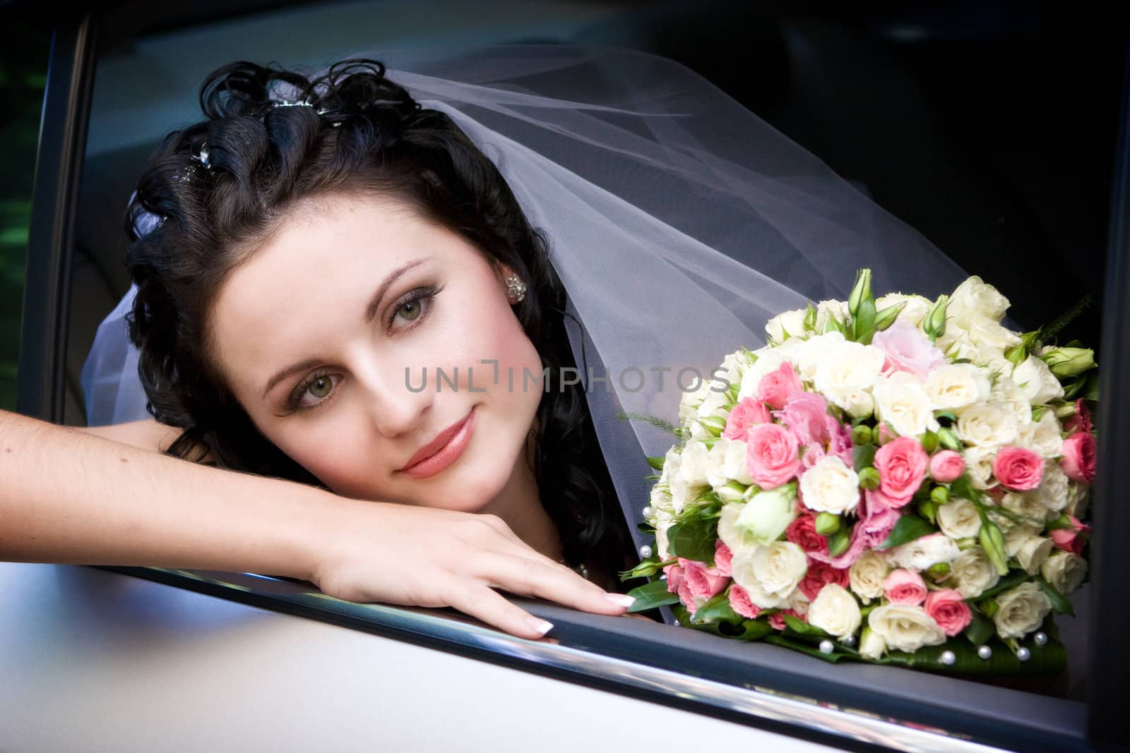 a bride with a bouquet of roses looks out of the car