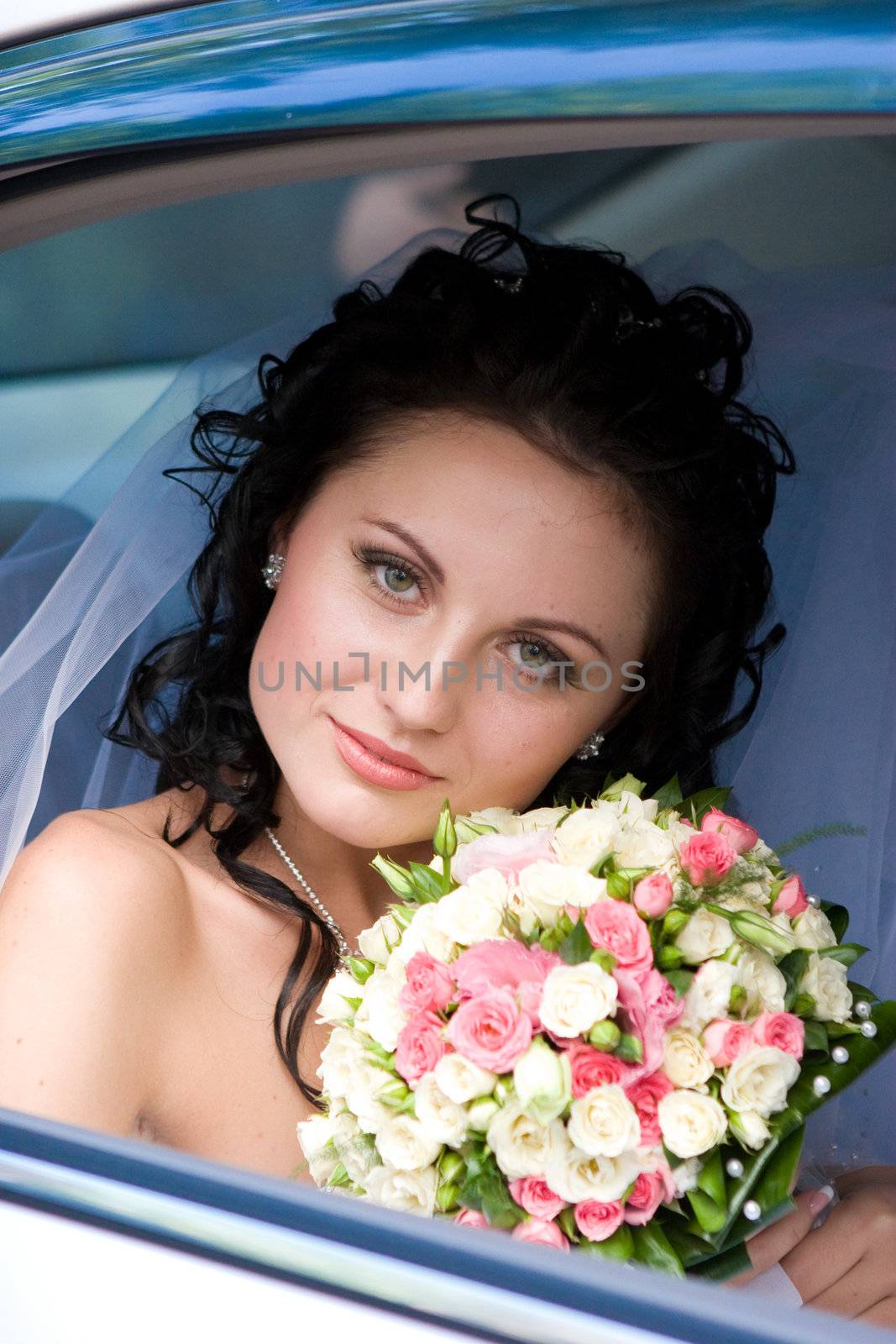 happy bride with flower bouquet siting in the car