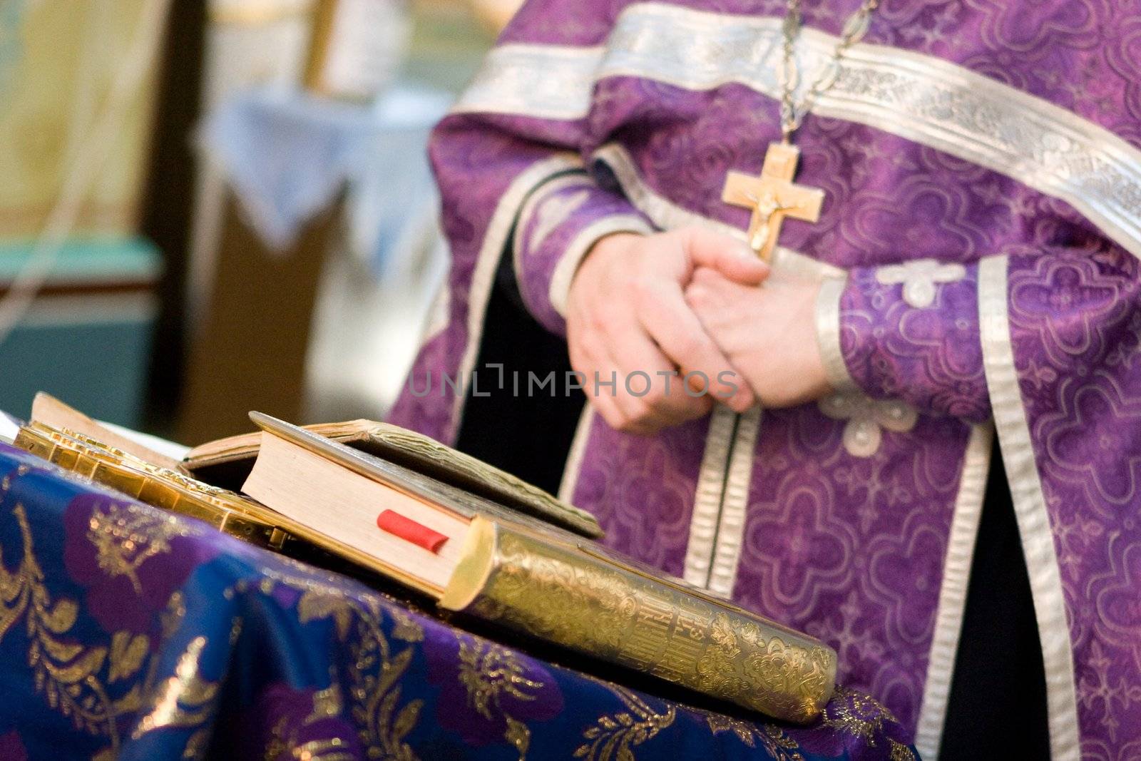 crossed hands of the praying priest and an open book