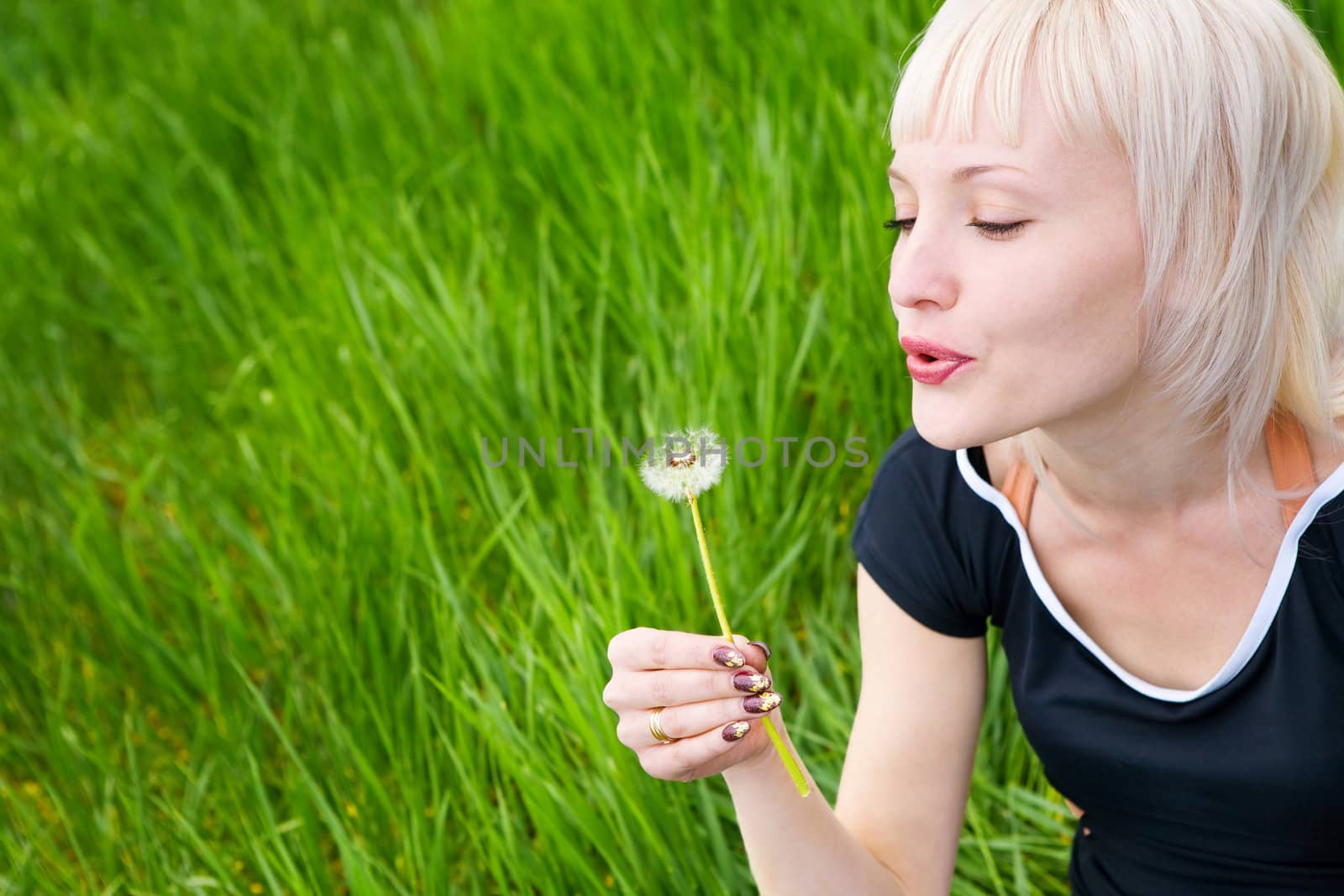 blond girl blowing on the dandelion