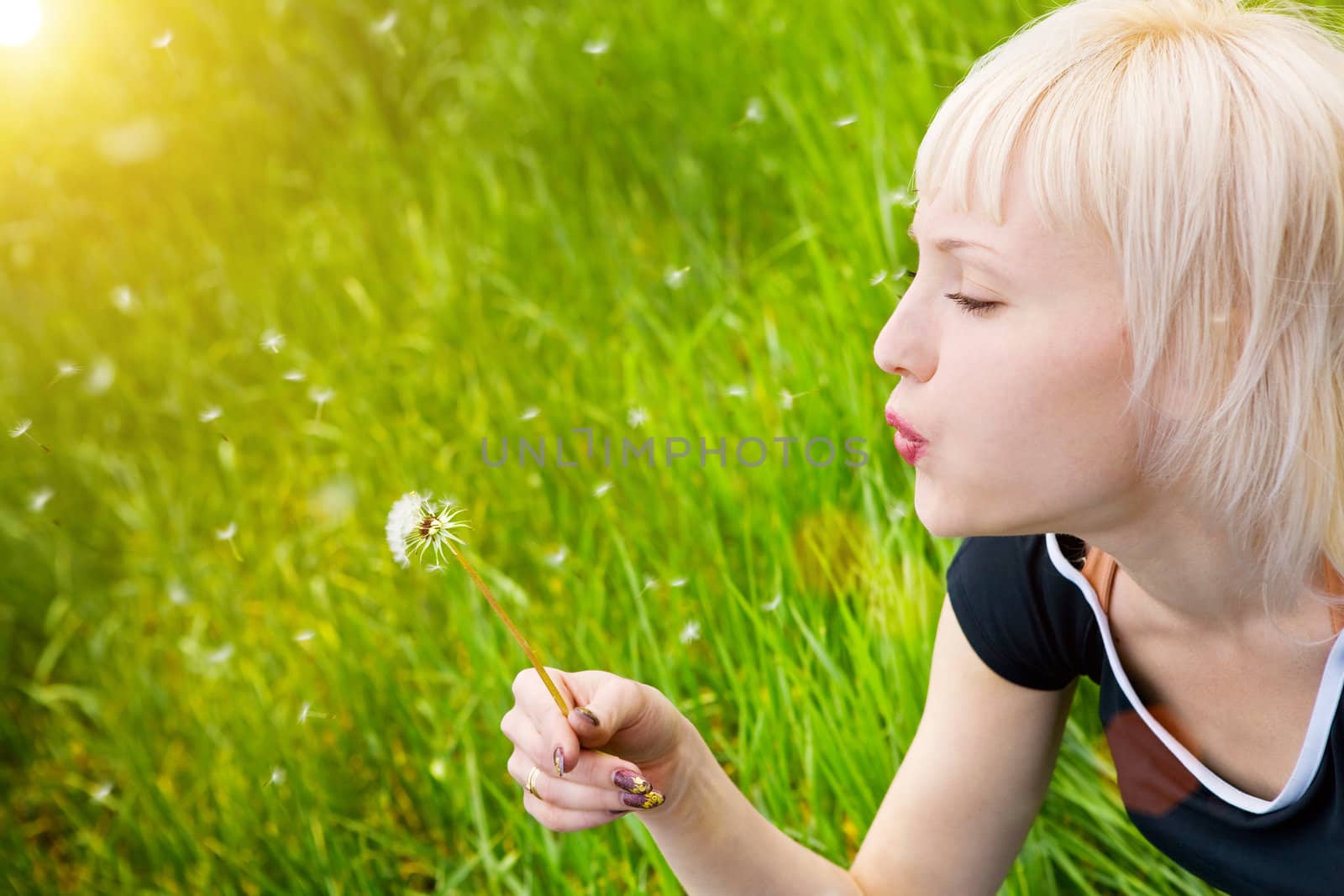 blond pretty girl blowing on the dandelion