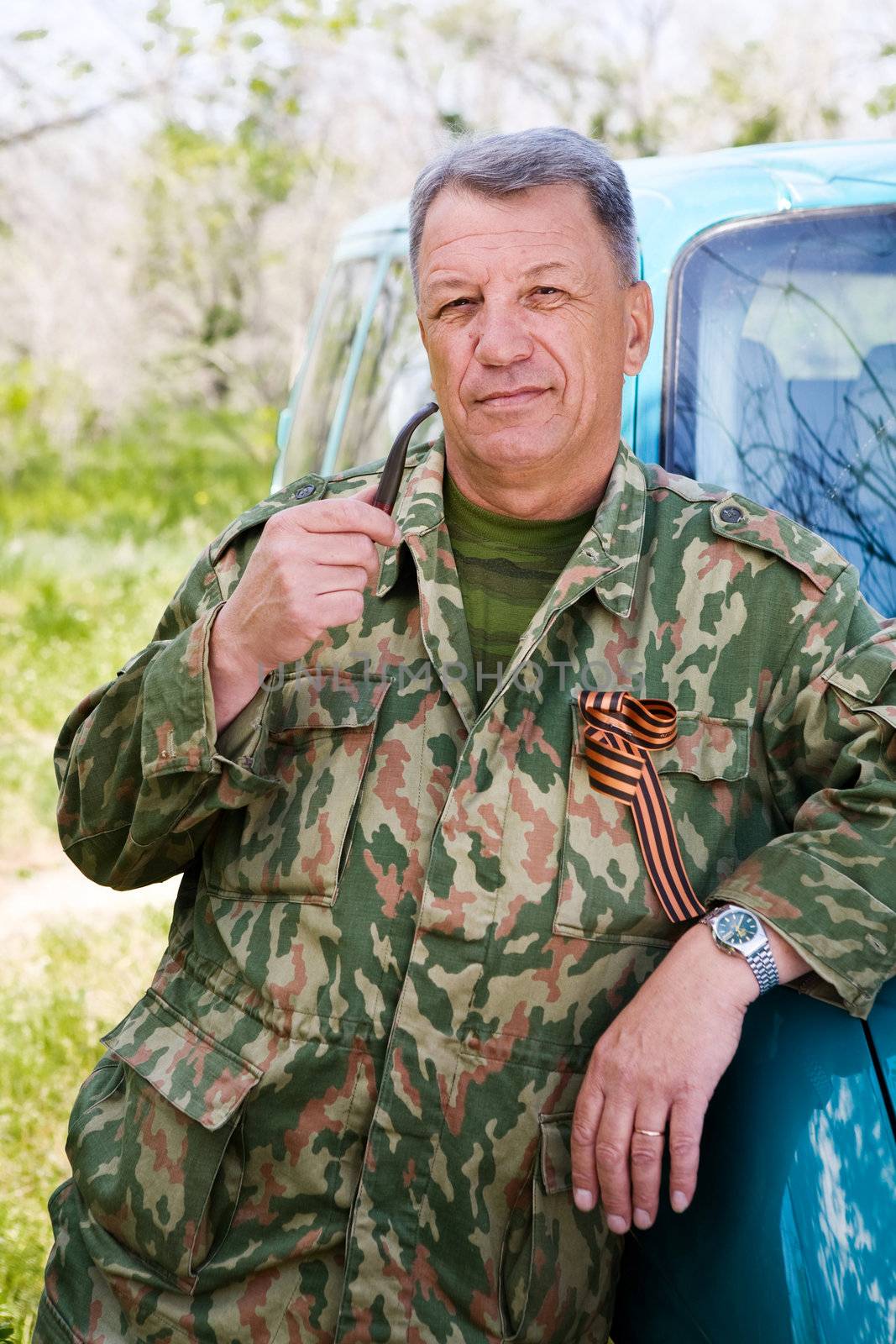man dressed in camouflage wear smokes pipe