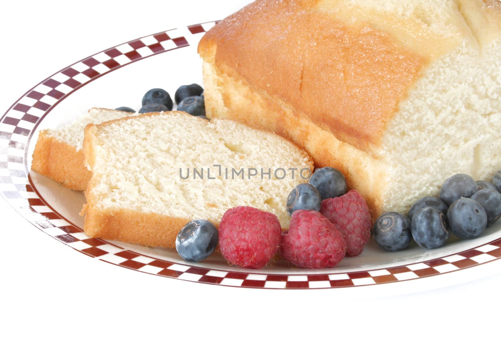 Pound cake slices with fresh fruit on a plate and shot on a white background.  