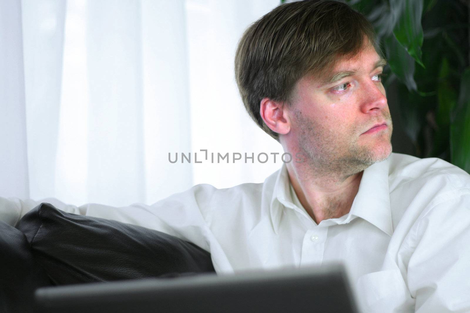 Handsome businessman working on laptop in casual attire.