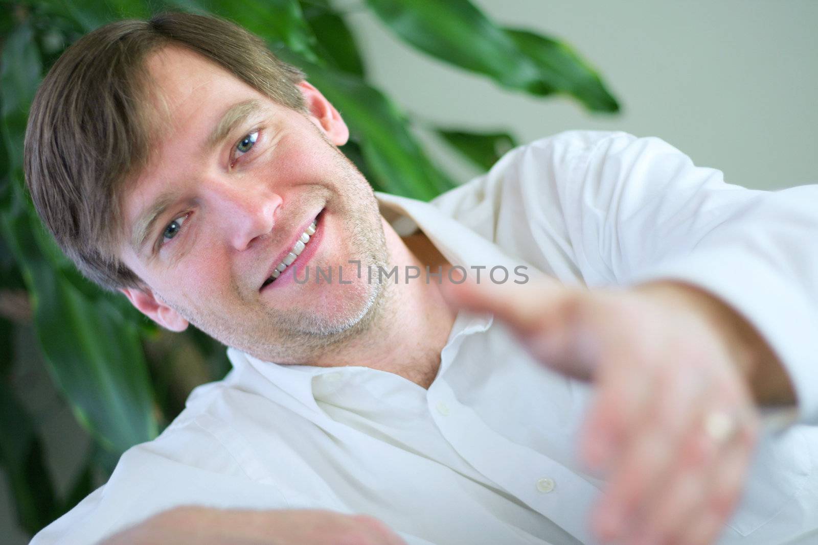 Handsome businessman in casual attire reaching out hand to give handshake.