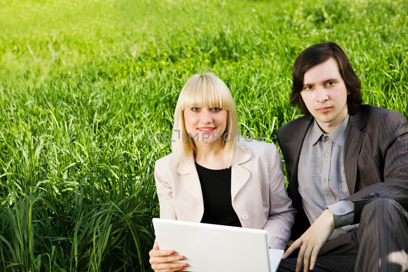 boy and girl dressd for business with laptop on the grass