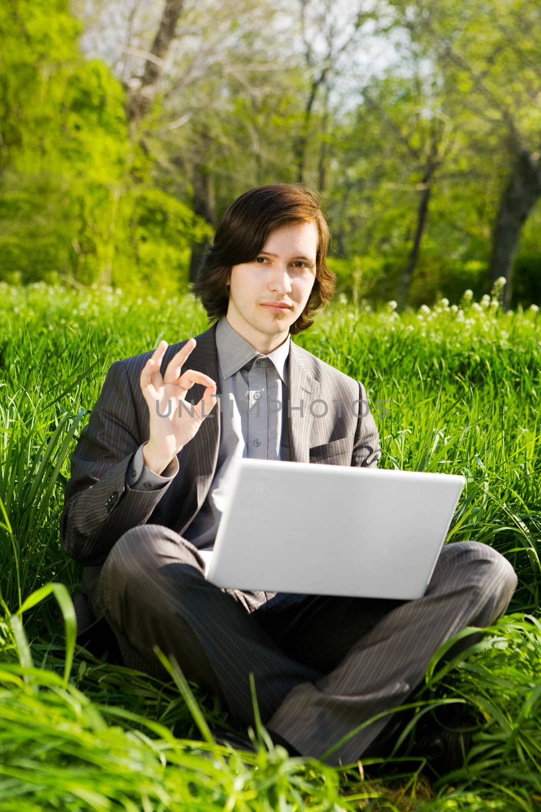 a young business man with a laptop on the grass field