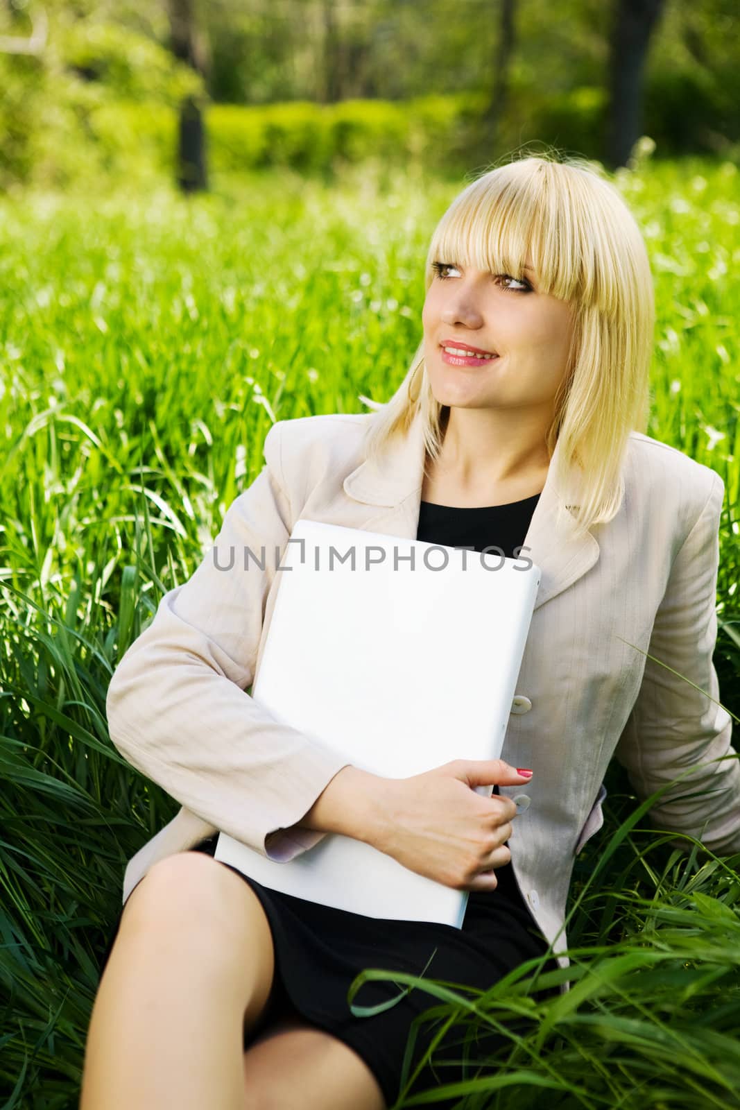 smiling student with laptop on the grass