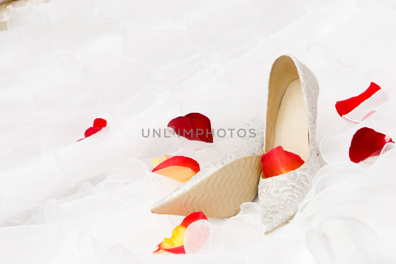white decorated shoes and red rose and tulip petails on the wedding dress