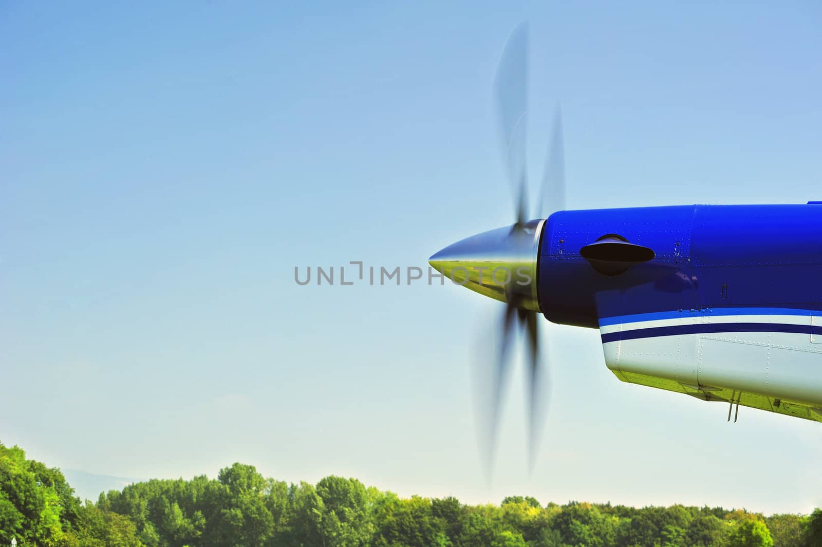 The propeller of an aircraft starting up, with motion blur on the blades. Space for text in the sky.