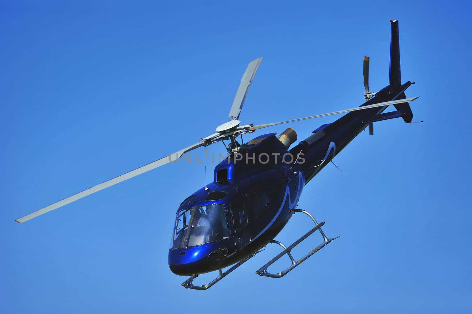 A helicopter coming in to land against a clear blue sky