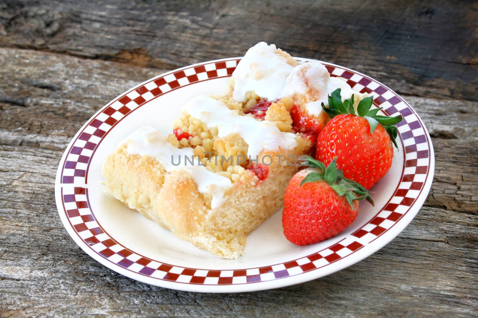 Fresh strawberry danish with icing and fresh strawberries on the side.