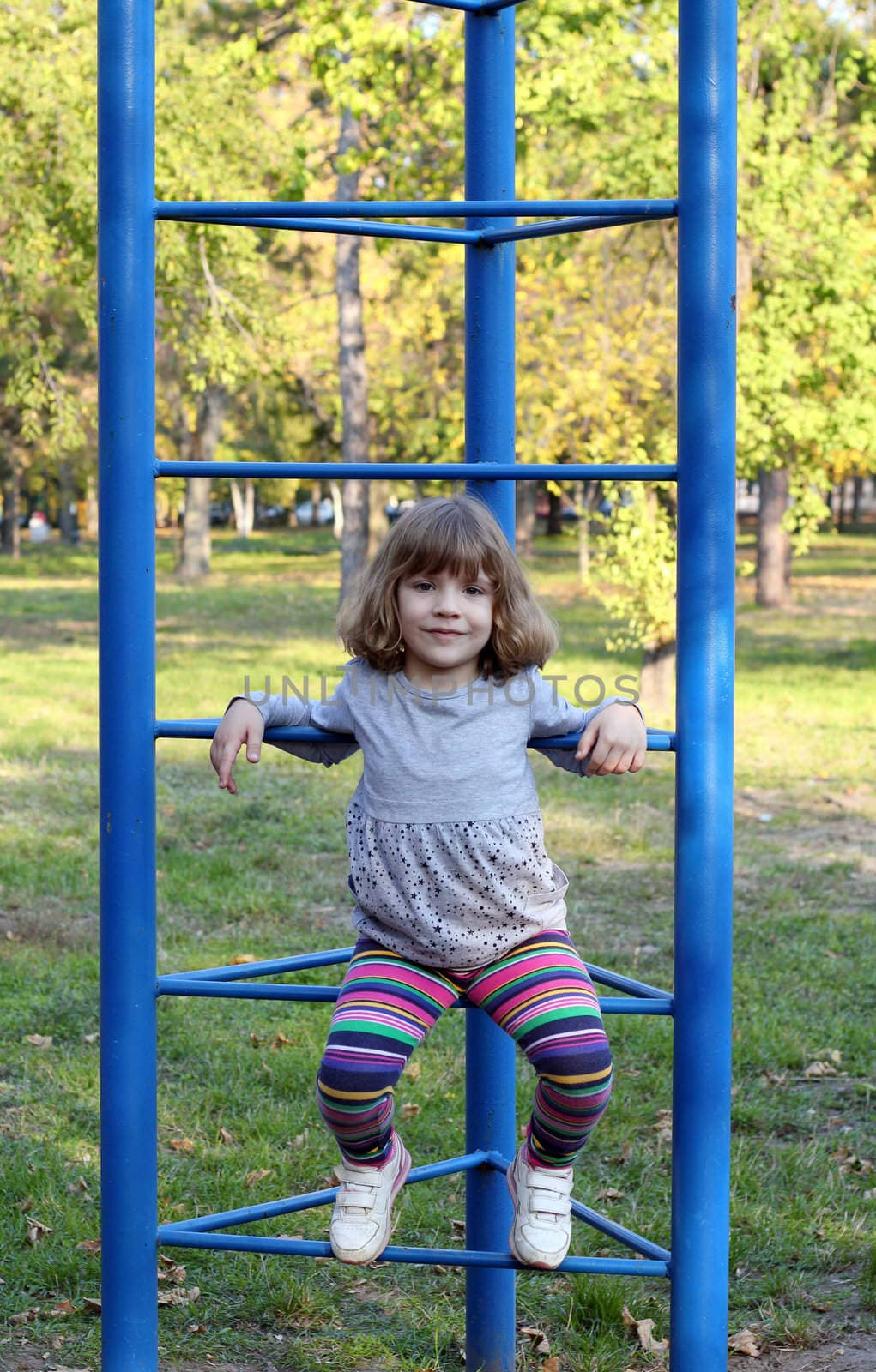 little girl on playground in park by goce