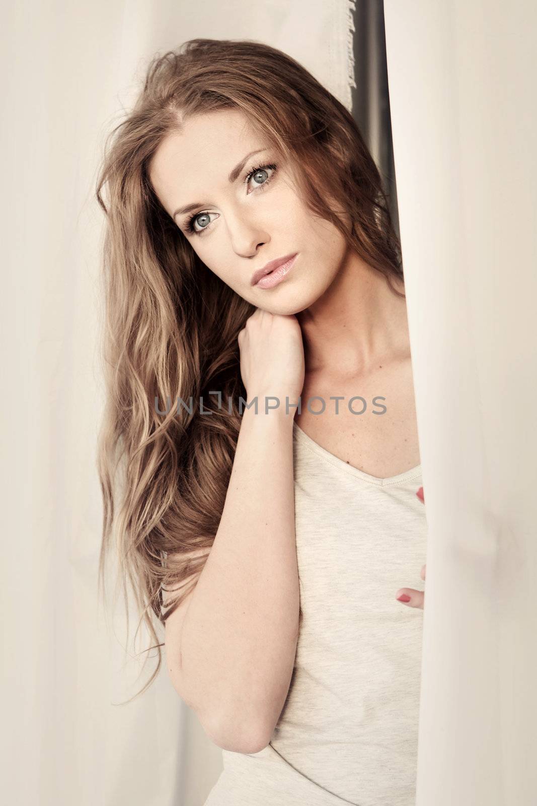 Beautiful girl looking through the curtains by robert_przybysz
