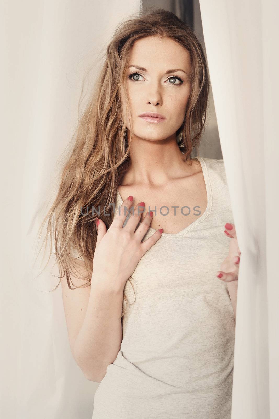 Beautiful girl looking through the curtains