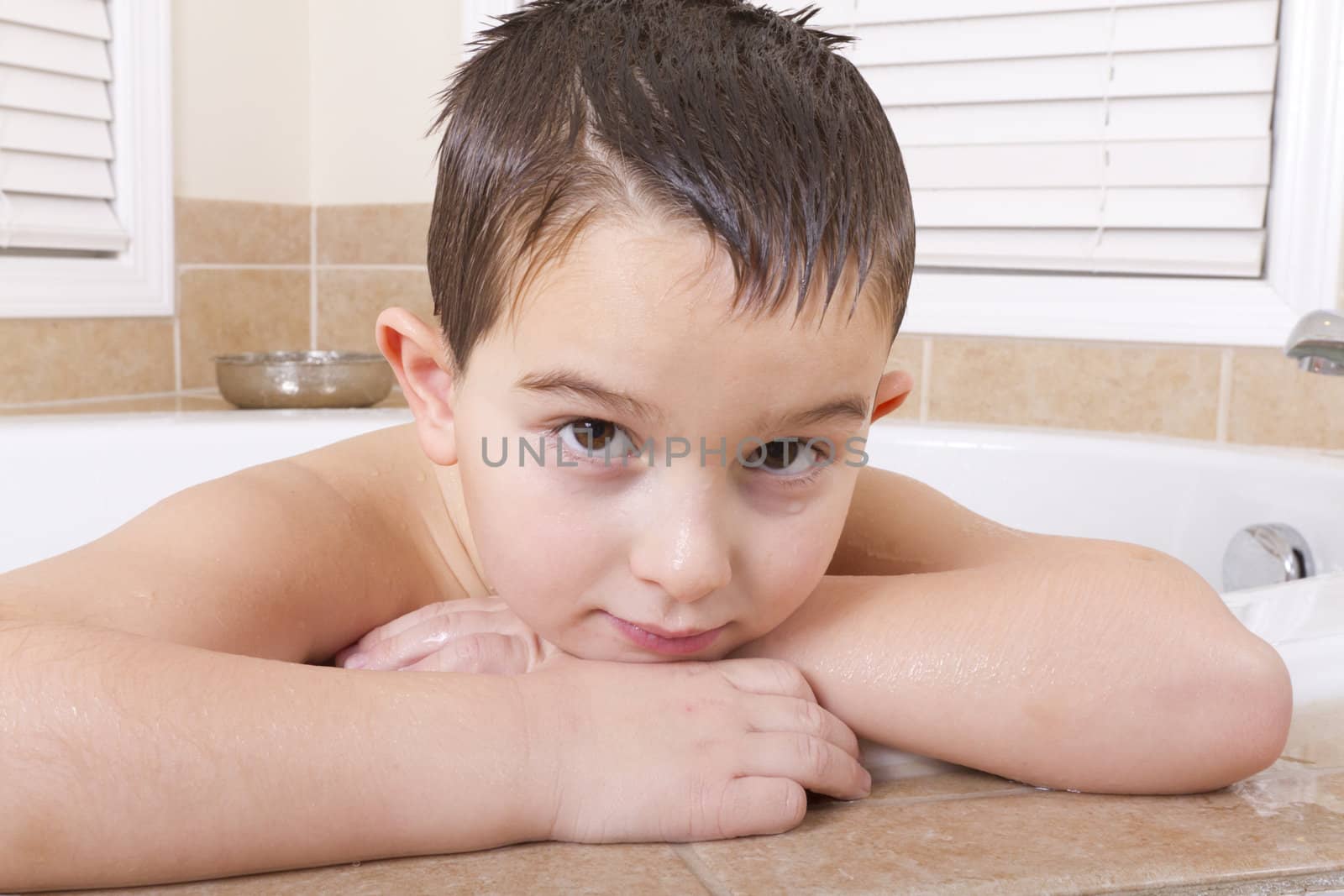 Seven years old kid looking at you ruminatively from a bath tub.
