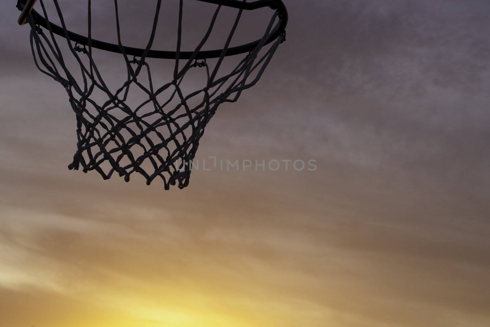 basketball hoop silhouette with an orange sunset