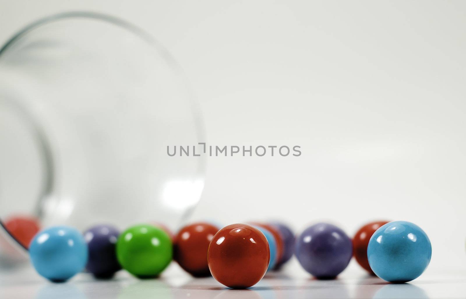 spilled colorful gumballs with a glass jar isolated on white background